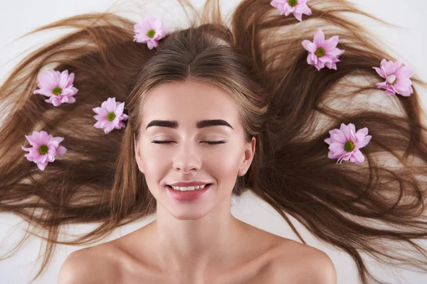 Encantadora jovencita con flores en el pelo sobre fondo blanco — Foto de Stock