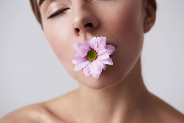 Okouzlující mladá dáma s dokonalou pletí drží růžový květ v ústech — Stock fotografie