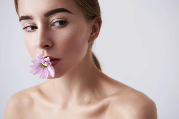 Charmante junge Dame mit rosa Blume im Mund — Stockfoto