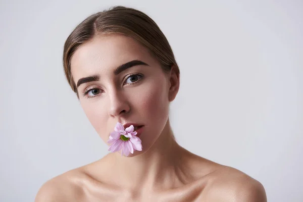Aantrekkelijke jongedame, houden van roze mooie bloem in mond — Stockfoto