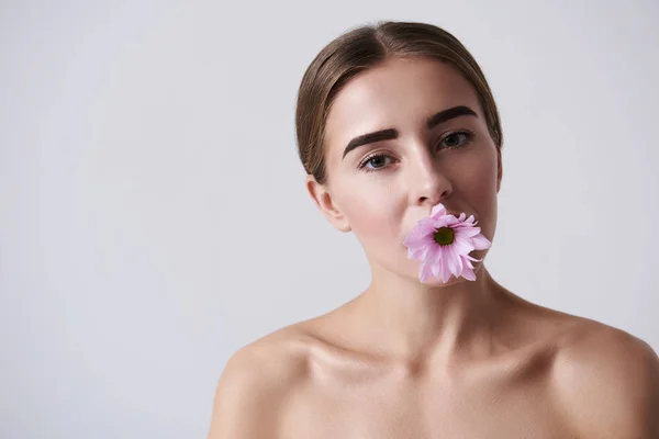 Atractiva joven mujer sosteniendo flor rosa en la boca —  Fotos de Stock