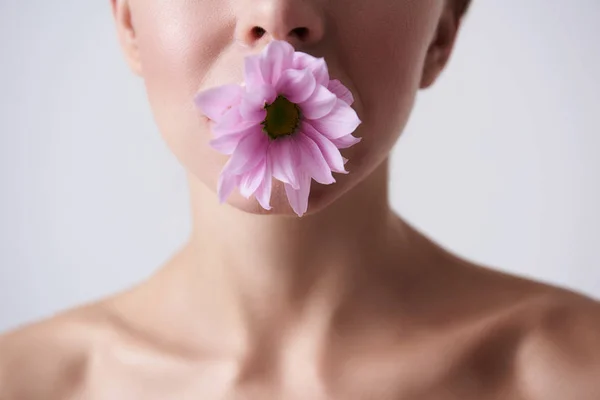 Mujer joven sosteniendo hermosa flor rosa en la boca — Foto de Stock