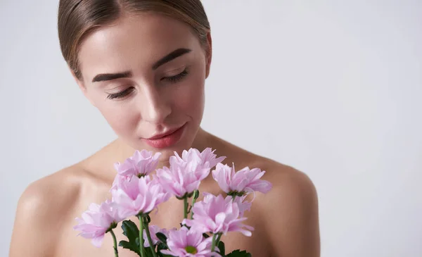 Okouzlující mladá žena držící krásné růžové květy — Stock fotografie