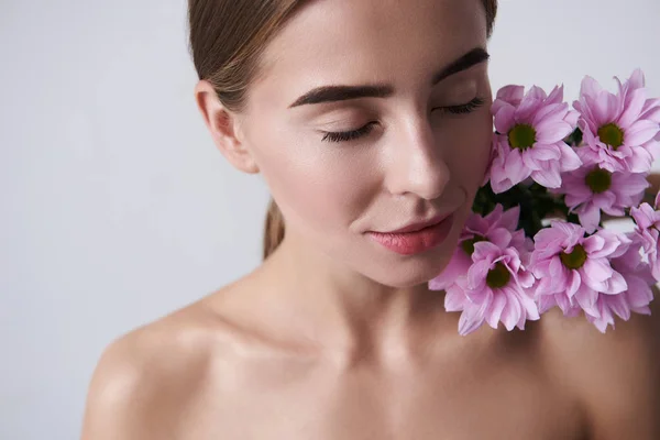 Vonzó fiatal nő, tartása szép rózsaszín virágokkal meztelen váll — Stock Fotó