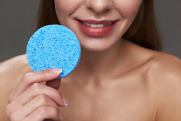 Kozmetik mavi sünger tutan olumlu genç bayan — Stok fotoğraf