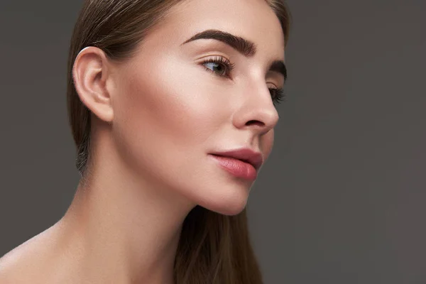 Charming young lady with perfect skin posing against gray background