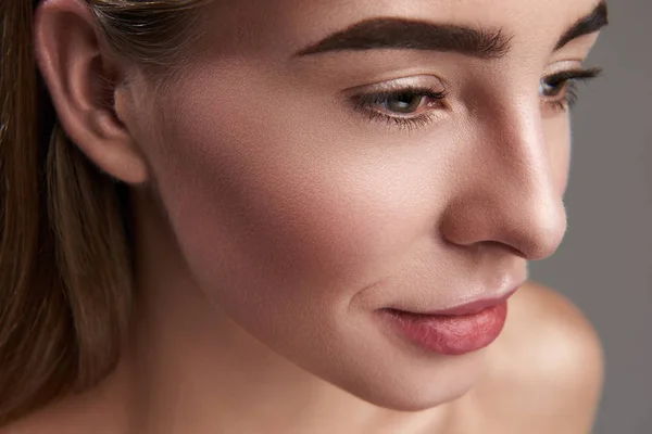 Vacker ung kvinna med naturlig makeup poserar på grå bakgrund — Stockfoto