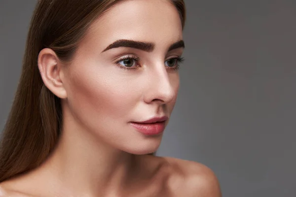 Charmante jonge dame met natuurlijke make-up geïsoleerd op een grijze achtergrond — Stockfoto