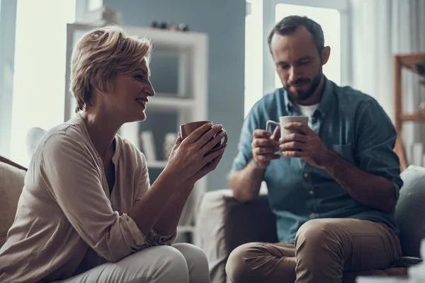 Двоє людей середнього віку п'ють чай і посміхаються — стокове фото
