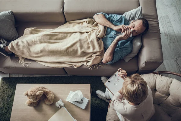 Hombre deprimido acostado debajo de la manta y mirando a su psicoterapeuta — Foto de Stock