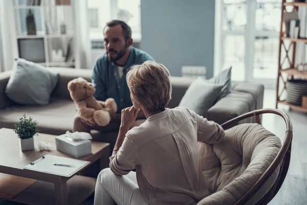 Vista rara del psicoterapeuta reflexivo y el hombre sentado con juguete — Foto de Stock