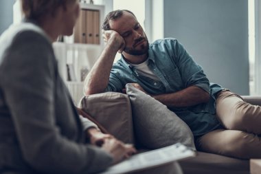 Çatık ve psikoterapist ile kanepede oturan üzgün adam