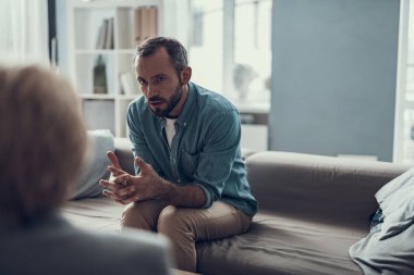 Kilitli parmakla oturan ve konuşurken sakallı adam