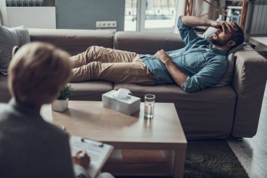 Kanepede yatan ve gözlerini kapatma mutsuz adam