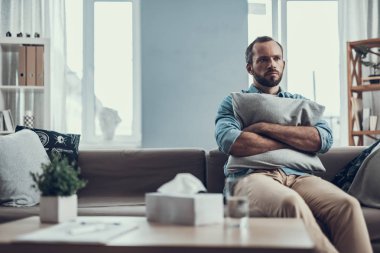 Çatık ve bir yastık sarılma ciddi sakallı adam