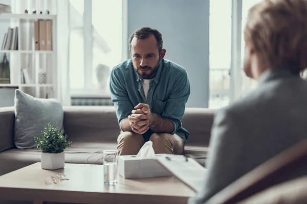 Sensibler Mann hält sich beim Sitzen mit Psychotherapeut die Finger zu — Stockfoto