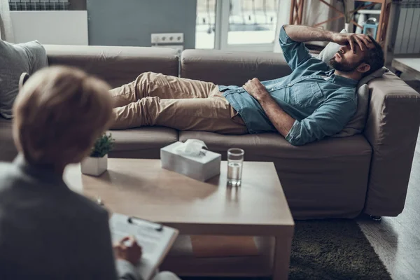 Kanepede yatan ve gözlerini kapatma mutsuz adam