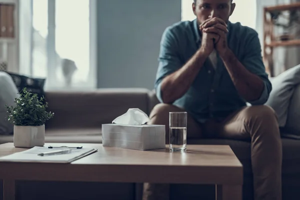 Enfoque selectivo del hombre preocupado sentado con agua y servilletas sobre la mesa — Foto de Stock