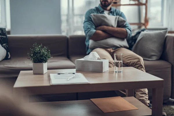 Enfoque selectivo de la mesa de café y el hombre sentado con su almohada — Foto de Stock