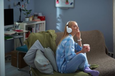 Evde müzik dinleme sıcak bir içecek olan büyüleyici kadın