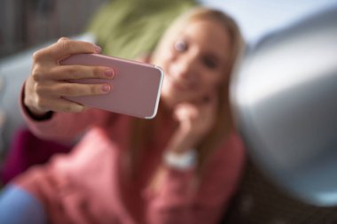 Pembe smartphone ile arka plan bulanık üzerinde genç bayan