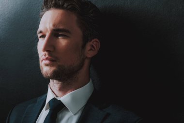 Yakın çekim yakışıklı adamın siyah duvarın yanında ayakta