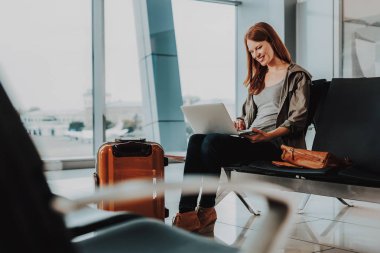 Gülümseyen kadın hava yoluyla seyahat etmeden önce not defterini kullanarak