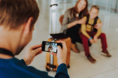 Cep telefonu ekranına bakarak baba odaklanmak. Onlar poz olan iken ailesi Havaalanı'nda hayal ediyor. Baba iyi çekim yapıyor denetliyor