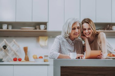 Genç Bayan ile mutlu anne mutfakta fotoğraflar izliyor