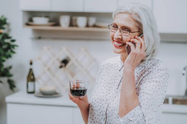 Mutfakta ayakta ve telefonda konuşurken çok mutlu kadın odaklanmak. O sabah sıcak içecek evde tatma. Kopya alanı sol tarafında