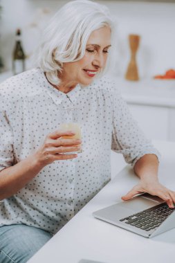 Sırıtan Olgun kadın suyu içme ve dizüstü bilgisayar kullanarak