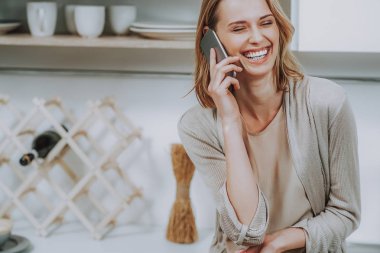 Kadın cep telefonu evde konuşma sırasında gülüyor