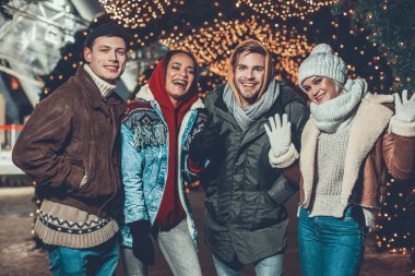 Mutlu insanlar sıcak giysiler aydınlatma önünde fotoğraf için poz