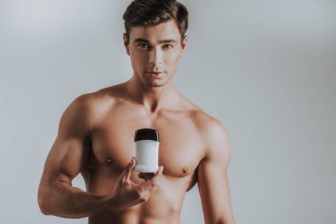 Yeni deodorant gösterilen ve sakin seyir üstsüz adam