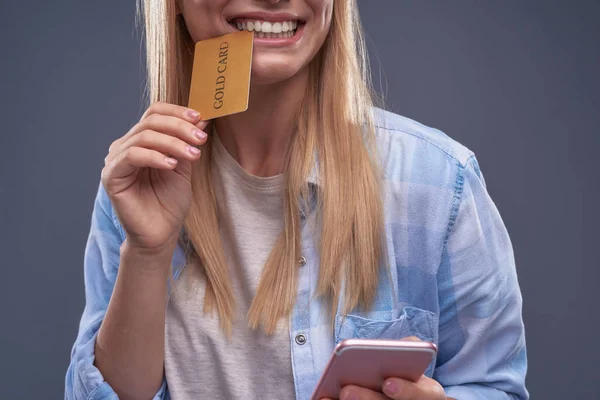 若い女性の携帯電話をかむとゴールド カード — ストック写真