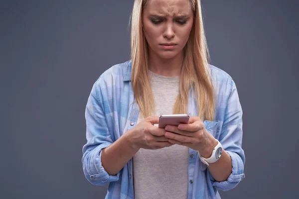 Naštvaná mladá dáma v modré košili pomocí mobilní telefon — Stock fotografie