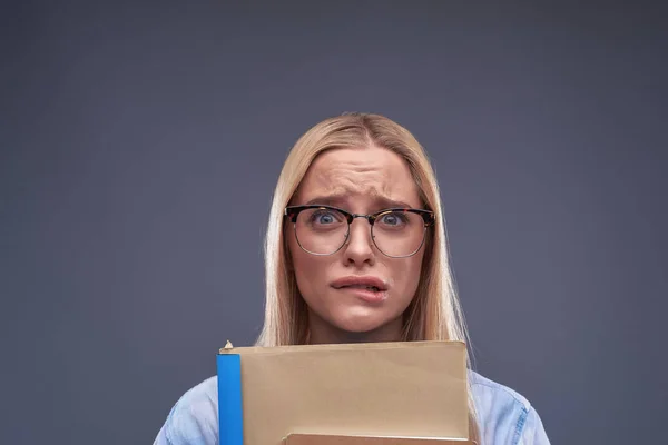 Young woman with documents feeling nervous and biting lips — Stock Photo, Image