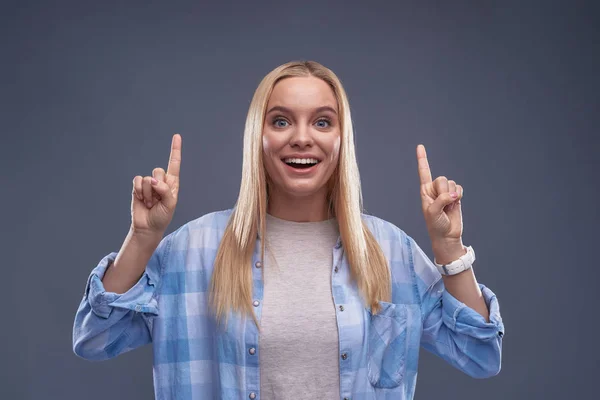 Allegro giovane signora in camicia blu alzando indice dita in su — Foto Stock