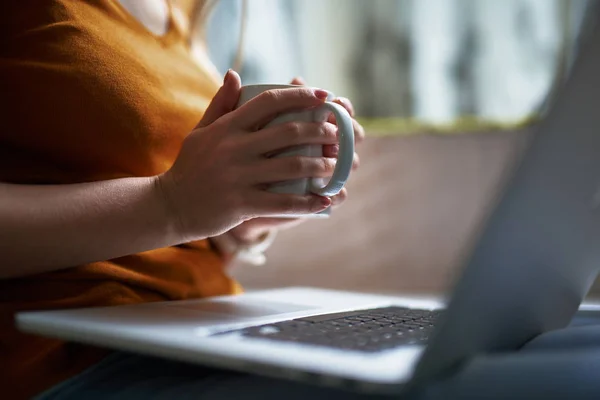 Jonge dame met laptop houden van kopje koffie — Stockfoto
