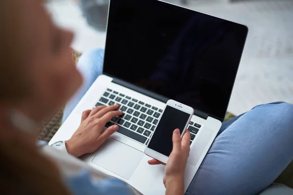 Giovane donna utilizzando il cellulare e il computer portatile bianco — Foto Stock