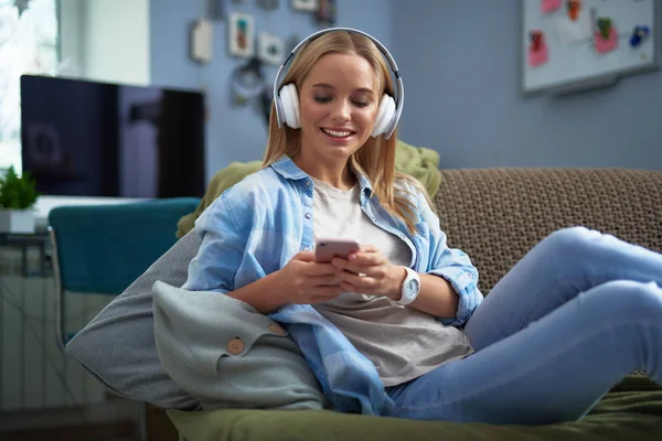 Schöne junge Frau hört Musik und benutzt Handy — Stockfoto
