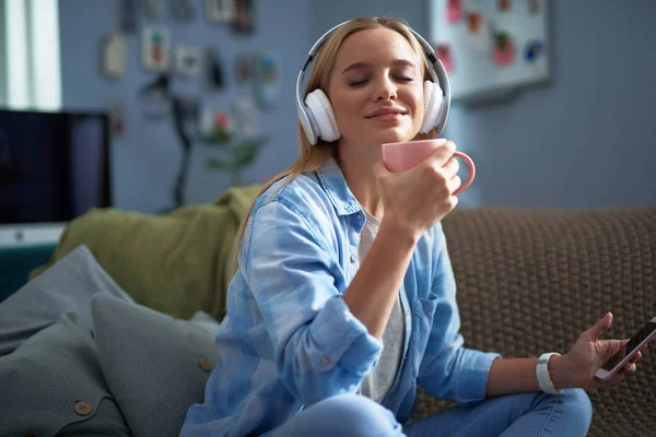 Schöne junge Frau mit Handy, Kaffee trinkend und Musik hörend — Stockfoto