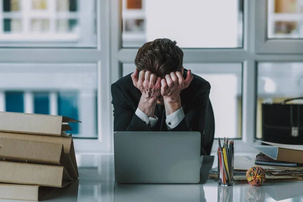 Hombre de negocios desesperado escondiendo su cara mientras está sentado en el lugar de trabajo — Foto de Stock