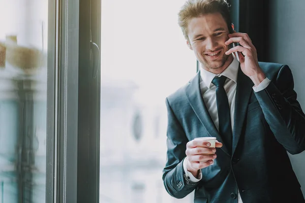 Uomo allegro in abito elegante sorridente e avendo conversazione telefonica — Foto Stock