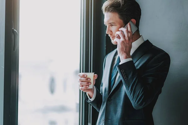 Uomo calmo che parla al telefono vicino alla finestra — Foto Stock