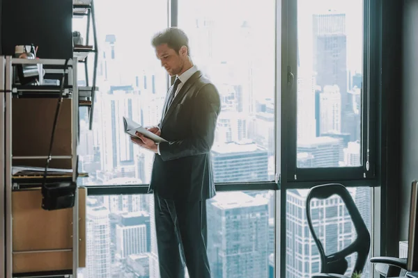 Hombre de negocios tranquilo de pie en su oficina y mirando las notas — Foto de Stock