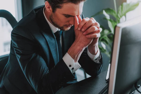 Tired young businessman touching his face and closing eyes