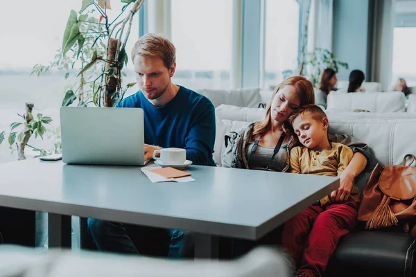 Koncentratu mężczyzna pracuje z laptopa w pobliżu Śpiące rodzina — Zdjęcie stockowe