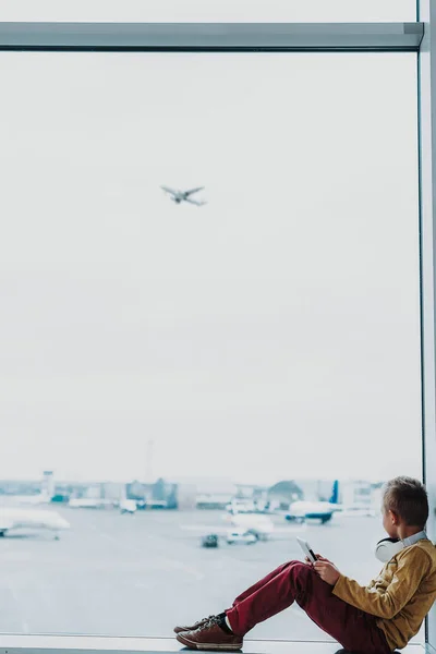 Menino com tablet está olhando para o avião do aeroporto — Fotografia de Stock