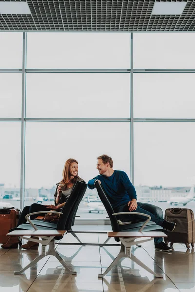 Alegre hombre y mujer se comunican en el salón del aeropuerto —  Fotos de Stock